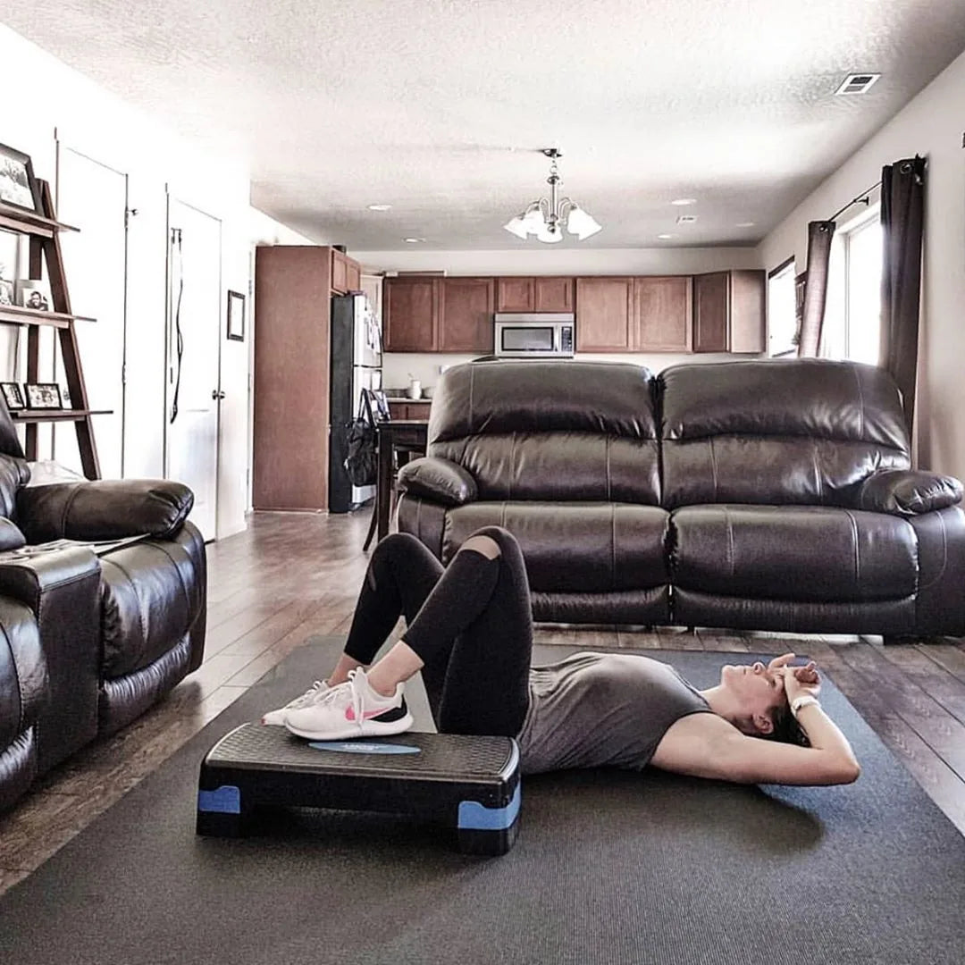 Woman doing a step workout on a large mat in an open living room