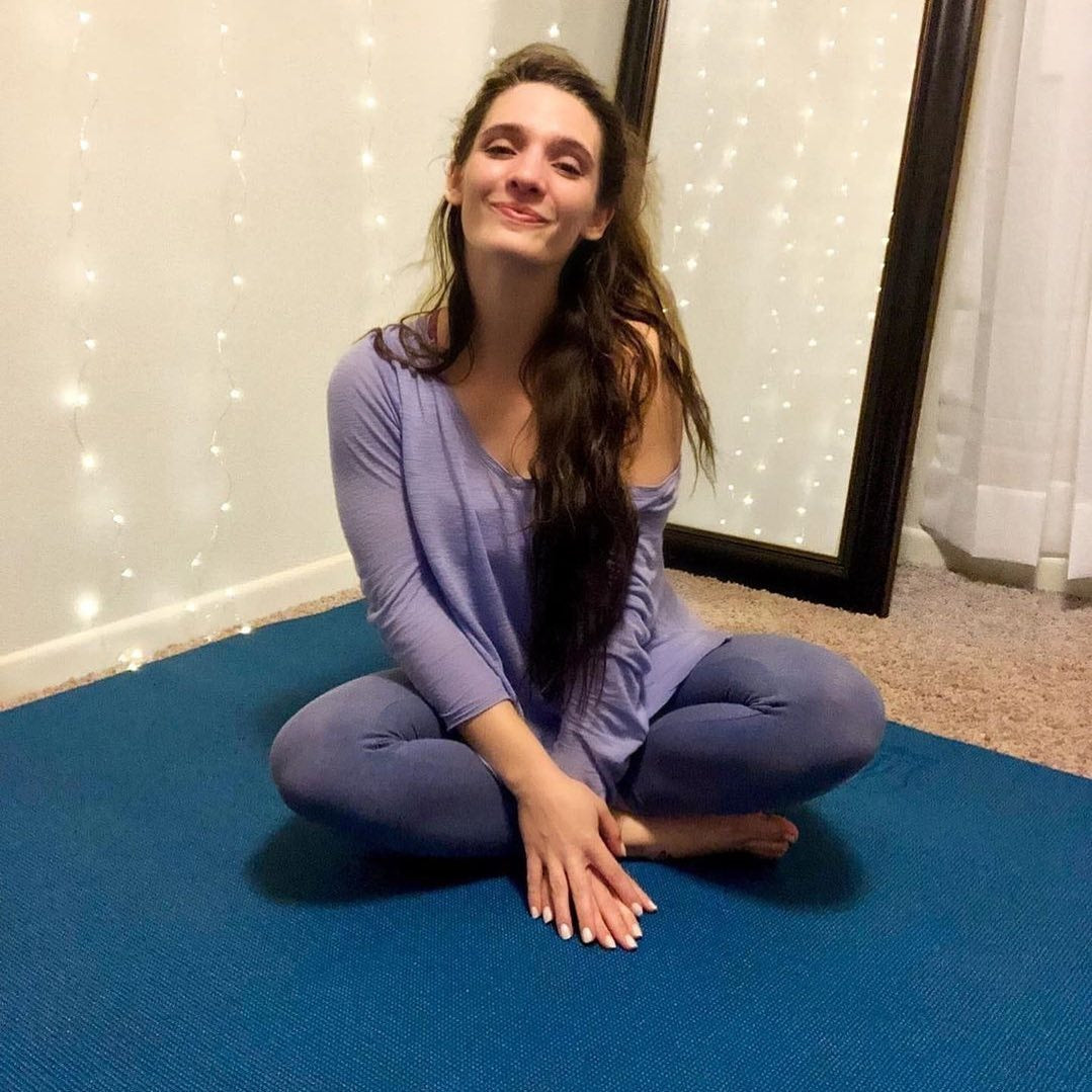 Smiling woman sitting cross-legged on a large Oasis Blue yoga mat