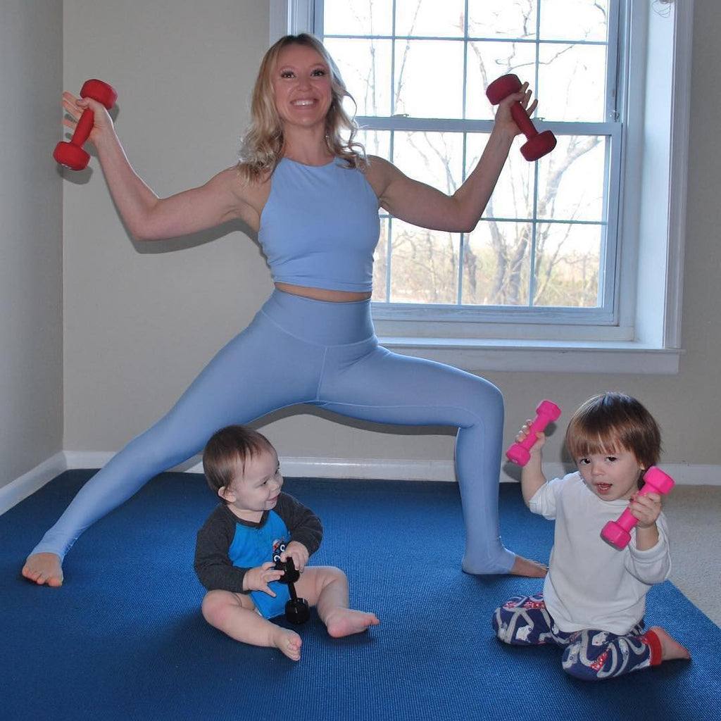 Mom in a wide squat with dumbbells beside her two kids on a large Midnight Blue exercise mat