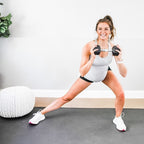 Woman in sneakers doing a dumbbell side lunge on a large black exercise mat