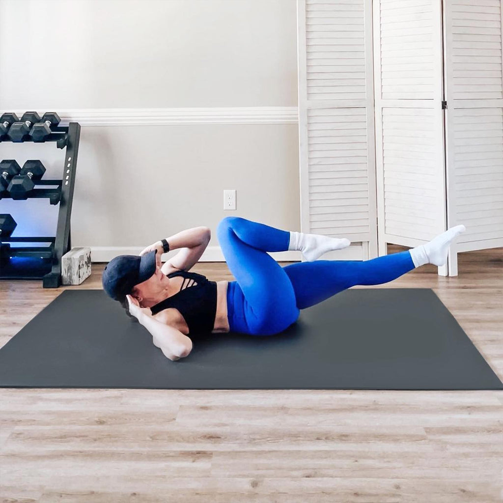 Woman doing bicycle crunches on a large black yoga mat