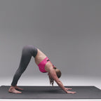 Woman in downward dog on a large black yoga mat