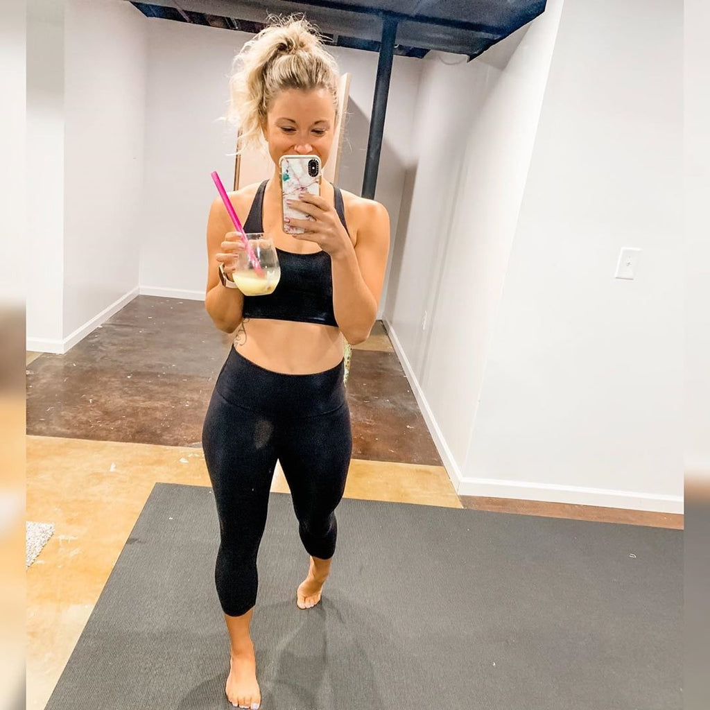 Woman taking a mirror photo on a large Silverback Gray exercise mat in her basement gym