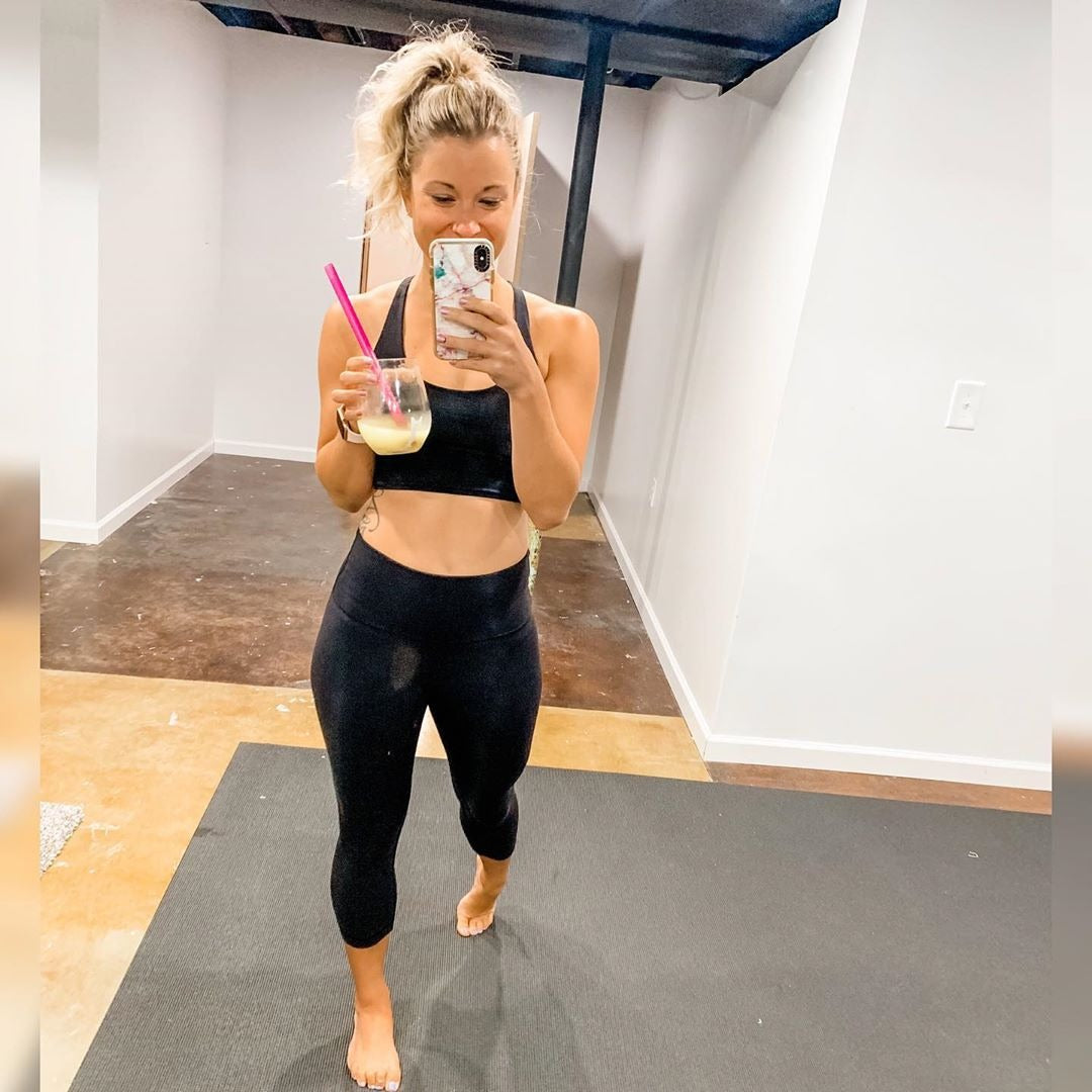 Woman taking a mirror photo on a large Silverback Gray exercise mat in her basement gym