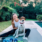 Smiling woman sitting with her dog on a large Silverback Gray exercise mat by the pool
