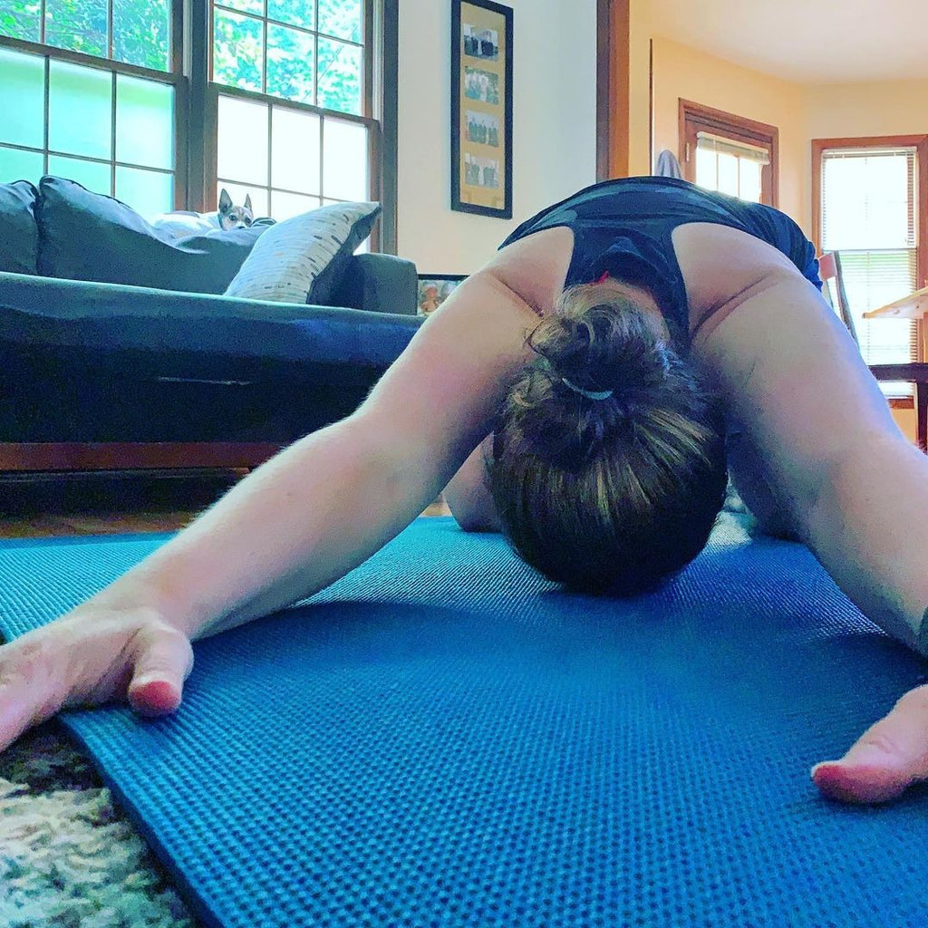 Woman in child's pose on a large Oasis Blue yoga mat in her living room