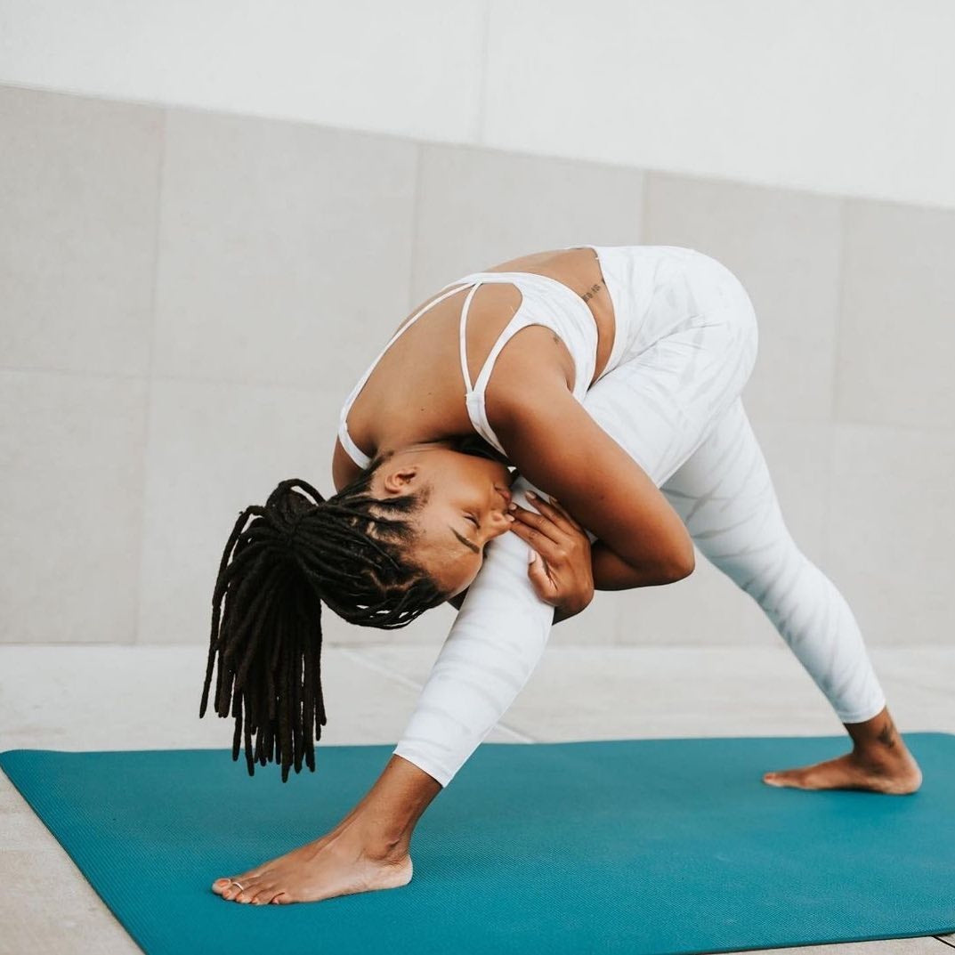 Woman in a deep standing forward fold on a large Oasis Blue yoga mat