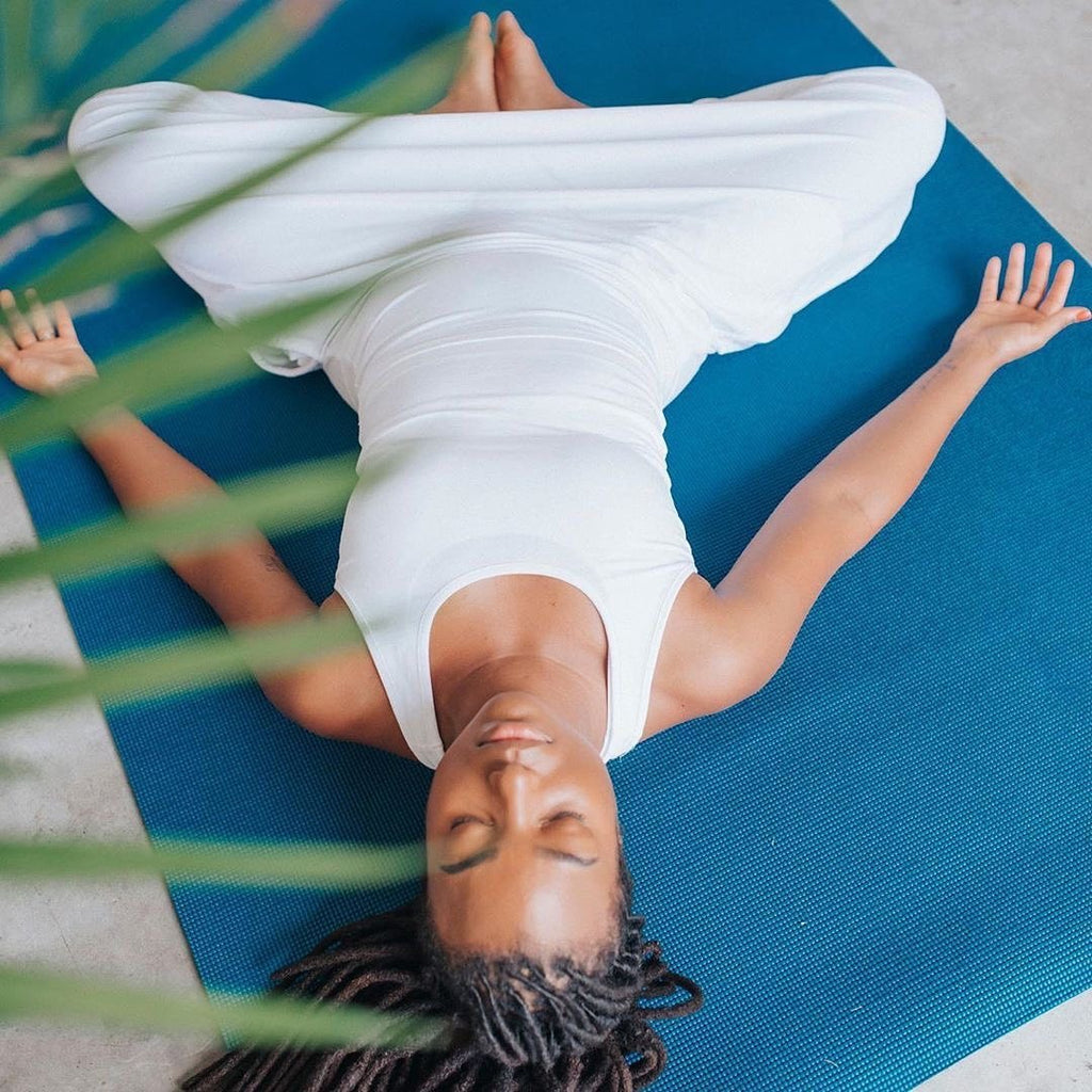 Woman resting with arms open on a large Oasis Blue yoga mat