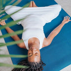 Woman resting with arms open on a large Oasis Blue yoga mat