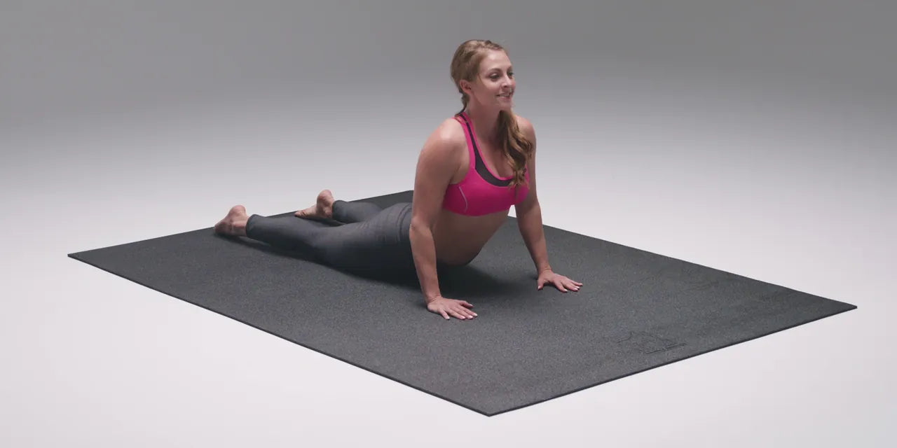 Woman in cobra pose on a 6 by 4 foot mat in a grey photo studio, the whole mat in view