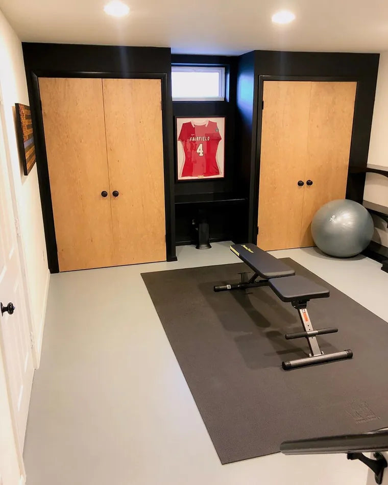 Home gym with a weight bench on a long exercise mat between two wooden closet doors
