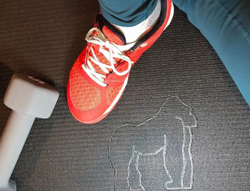 Close-up of a red sneaker and a dumbbell on the black exercise mat